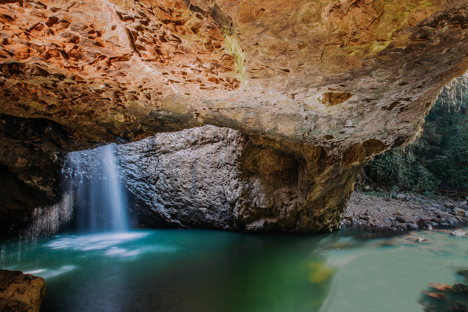 The Natural Bridge cave with water flowing into a rock pool below.