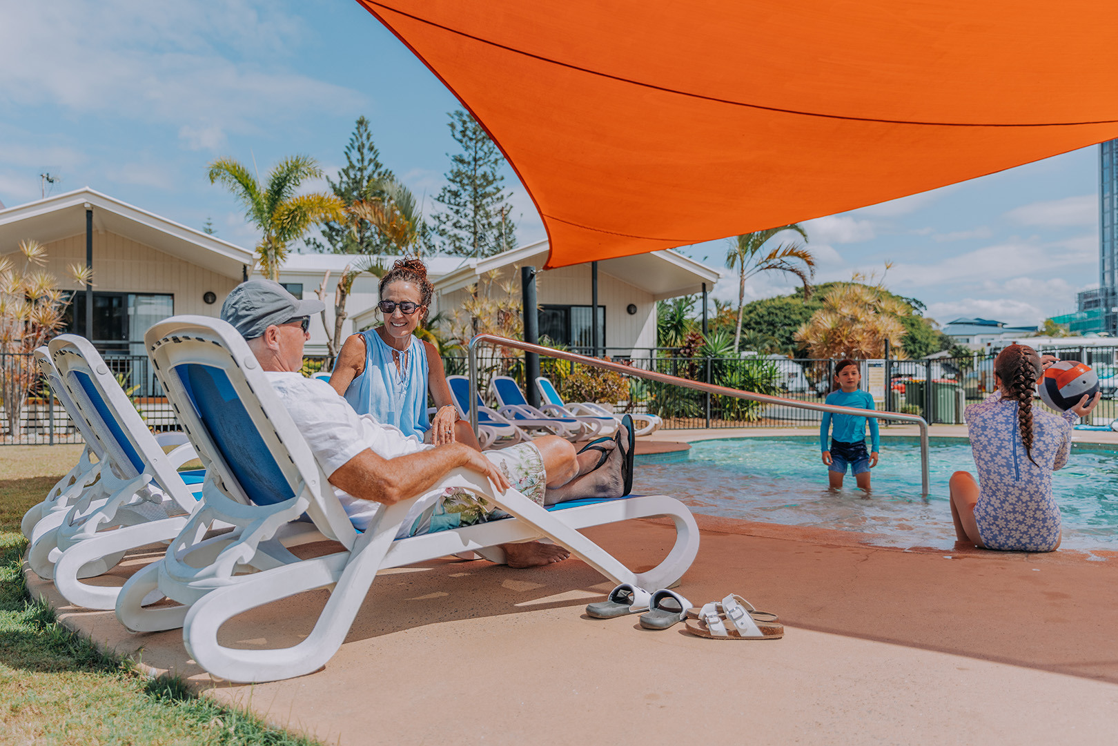 Parents on sun loungers relaxing as they watch their children play in the pool at Broadwater Tourist Park.