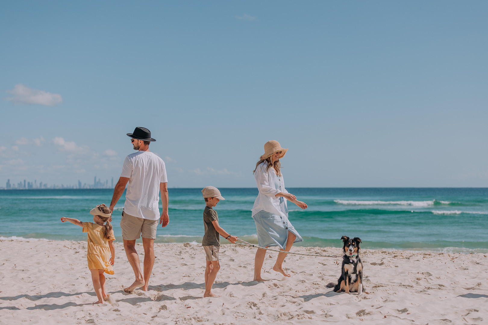 A young family walking their dog on the beach at Kirra.
